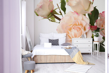 Stylish interior of bedroom with beautiful rose flowers on wall