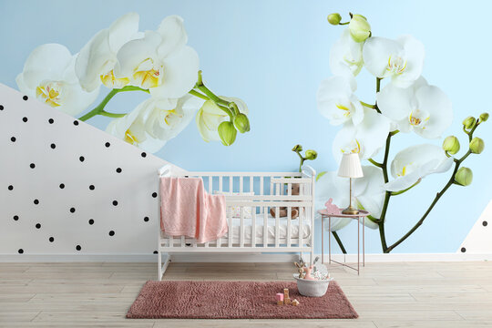 Stylish interior of children's room with beautiful orchid flowers on wall