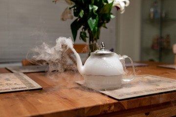 Glass teapot emit stream  of white steam from dry ice dissolved in water