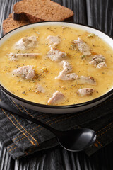 Artsoppa is a Swedish soup that is predominantly yellow split peas and meat close up in the plate on the table. Vertical