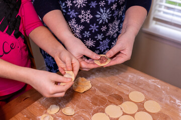 Mother teaching daughter how to make dumplings.