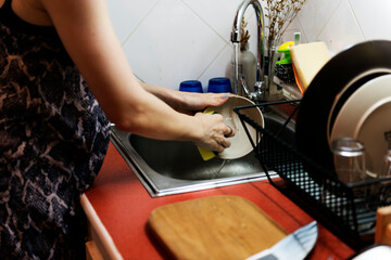 Woman is cleaning dishes at home.