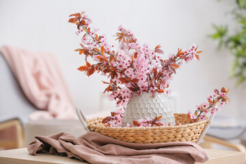 Vase with beautiful blossoming branches on table in room