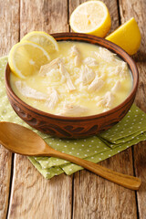 Kotosoupa is a delicious and hearty Greek chicken soup closeup in the plate on the table. Vertical