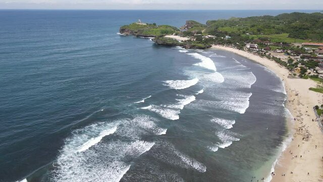 Aerial view of Baron Beach in Gunung Kidul, Indonesia with lighthouse and traditional boat. 