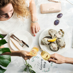 A couple in a date raising champagne glasses and having fresh oysters