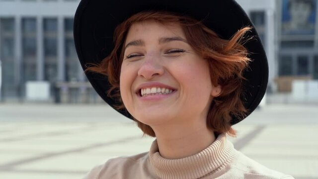 Beautiful smiling woman wearing casual clothing and stylish hat looking at camera. Positive lifestyle concept. Slow motion