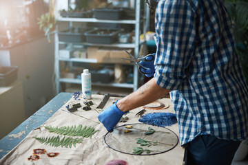Obraz na płótnie Canvas Young man in gloves making herbarium in workshop