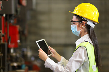 Asian woman engineering manager with facial mask in safety hard hat and reflective cloth is...