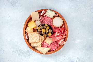 Charcuterie and cheese board, shot from above. Prosciutto di Parma ham, blue cheese, olives and crackers, gourmet antipasti on a slate table