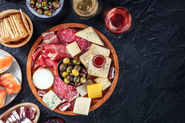 Charcuterie and cheese board with wine, overhead flat lay shot on a black background with a place...