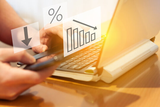 A man is studying the fall in family income at the computer and smartphone. The concept of a decrease in wages and an increase in poverty