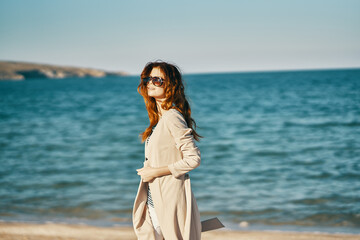 Fototapeta na wymiar romantic woman in coat and t-shirt on the beach near the sea in the mountains