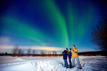 Company of friends tourist looks aurora northern lights night at forest, soft focus © Parilov