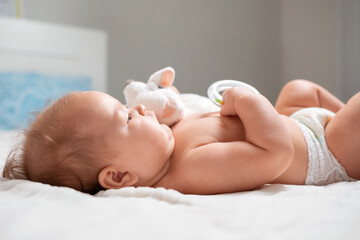 A baby is lying with a toy in the cradle. Close-up. The concept of parenthood