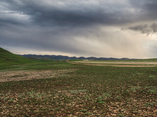 Green highland pasture against the background of rainy and foggy hills.