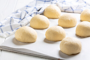 Wheat buns rising on a baking sheet.