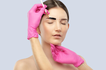 Make-up artist makes markings with white pencil for eyebrow and paints eyebrows. Professional...