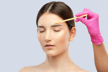 Fototapeta premium Makeup artist does facial hair removal procedure. Beautiful girl with blue eyes having Permanent Make-up on her Eyebrows. Professional makeup.