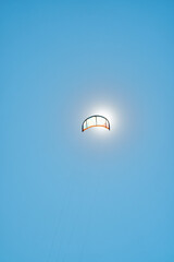 Bright colorful kites for surfing fly high across clear blue sky eclipsing the sun at tropical...