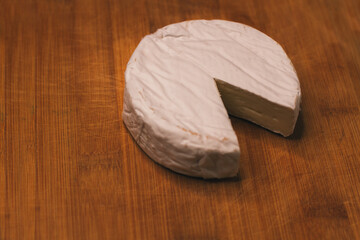 A piece of cheese is cut off. Brie or camembert cheese. Slicing a cheese plate. Cheeses made from natural cow's milk. Farm products. Delicacies. Copy space