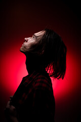 Portrait of a young man with long hair on a red and black background