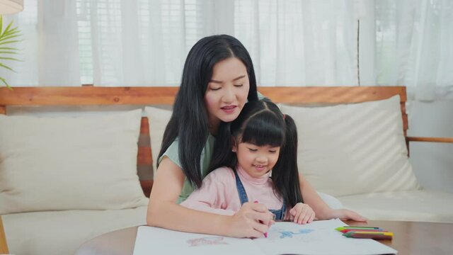 Asian little girl painting picture with mother in the living room.