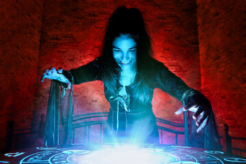 The witch conjures on a mysterious table in the stone basement of a mysterious house illuminated by blue and red light