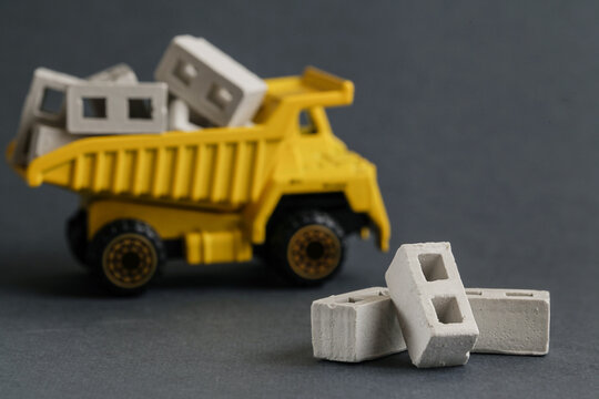 Autoclaved aerated concrete. Toy dump truck delivering concrete block. Transportation construction materials on building site. Copy space. Selective focus