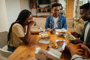 Four black friends having take out food at home together