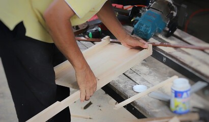 A carpenter is working on assembling a wooden table set. 