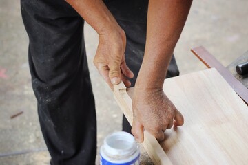 A carpenter is working on assembling a wooden table set. 