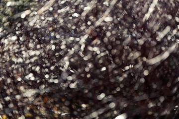 Blurry background with sun glare and rays forming a beautiful bokeh of branches and foliage in the park