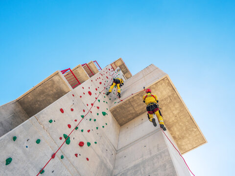 Professional climbers in uniform hanging on ropes