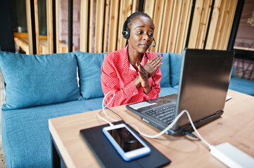 African american woman works in a call center operator and customer service agent wearing microphone headsets working on laptop.