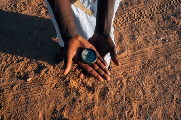 Crop black person showing compass in desert