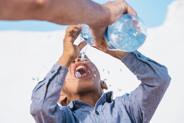 Ethnic boy drinking water near soldier