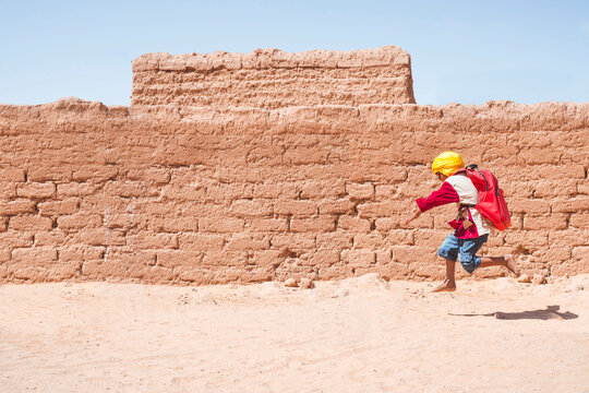 Ethnic kid running to school in desert