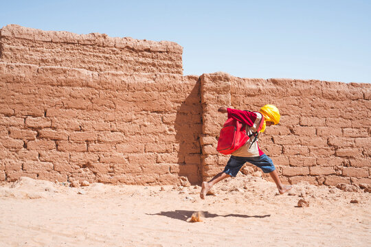 Ethnic kid running to school in desert
