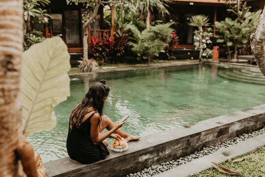 Woman sitting on edge of pool with smartphone