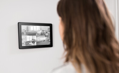 automation, security and technology concept - woman having video surveillance on tablet pc computer at smart home