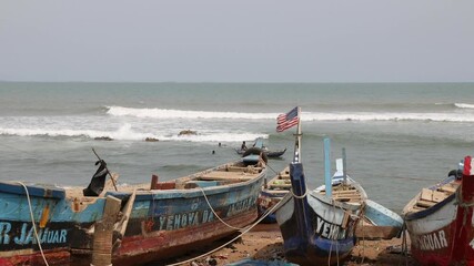 Fishing village beach wooden boats Accra Ghana. Old handmade fishing boats fish together at night for the local village.  Families live in  poverty. - Powered by Adobe