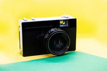 Old vintage analog camera isolated on a yellow and green background