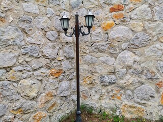 Street lamp. Black pole and lamp. Stone wall background.