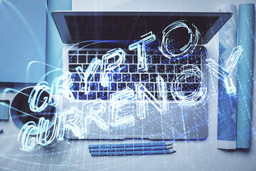 Blockchain theme hologram drawings over computer on the desktop background. Top view. Multi exposure. Concept of cryptoeconomy.