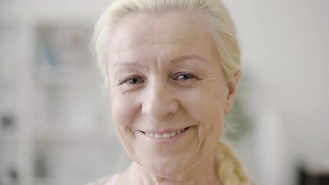 Smiling senior woman holding old photo of herself, remembering past and youth