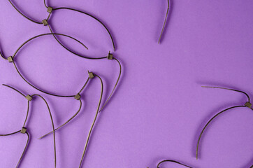 Black wire ties on lilac background. Old cut plastic ties.