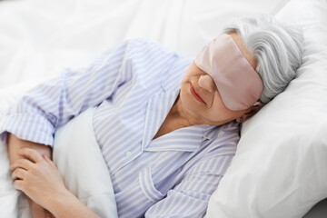 old age and people concept - senior woman with eye mask sleeping in bed at home bedroom