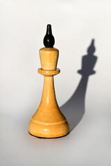 wooden white chess king on a white background and a shadow from it. International Chess Day....