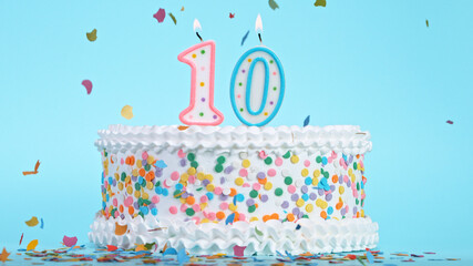 Colorful tasty birthday cake with candles shaped like the number 10. Pastel blue background.